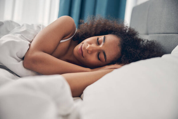Serene curly-headed female lying on the pillow