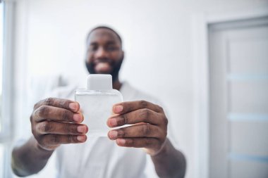 Parfümünü tutan erkek ellerine odaklanmış bir fotoğraf.
