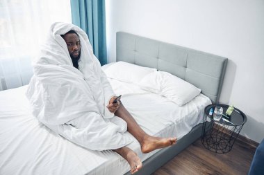 Üzgün, genç, esmer adam evde yalnız.