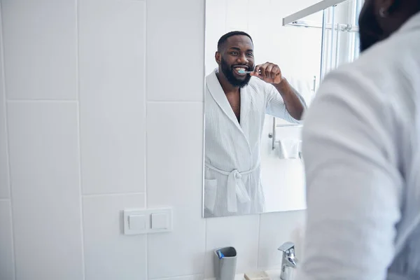 Positivo encantado hombre de piel oscura mirando su reflejo — Foto de Stock