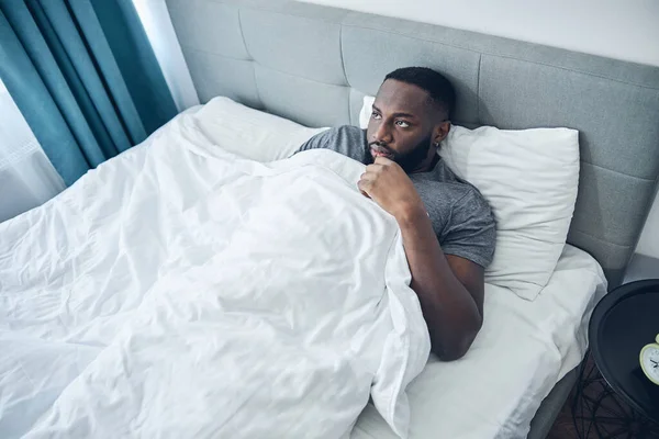 Aburrido hombre internacional acostado en su cama — Foto de Stock