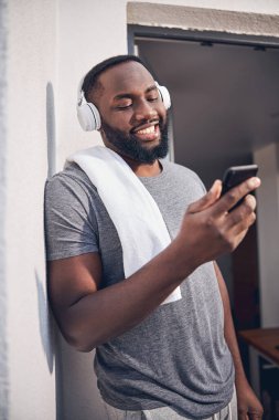 Neşeli erkek, güneşli sabahı balkonda geçiriyor.