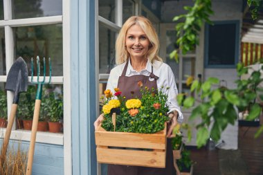 Süslü çiçekleri olan gülümseyen bir bayan.