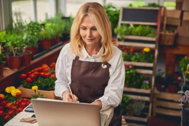 Çiçekçide çalışan konsantre sarışın bayan.