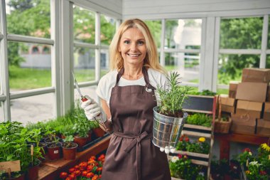 Gülümseyen kadın botanikçi elinde biberiye tohumu tutuyor.
