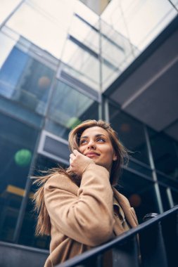 Çekici bir kadın dirseğini tırabzana yaslıyor.