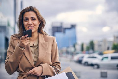 Elinde bir aletle gülümseyen bayan mesafeye bakıyor.