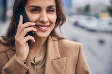 Gülümseyen bir kadın akıllı telefondan arıyor.