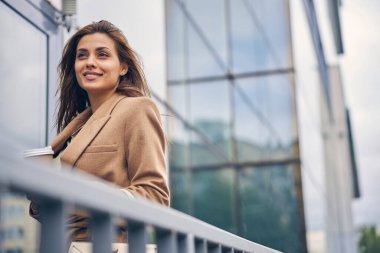 Dışarıda duran kağıt bardaklı güzel bayan.