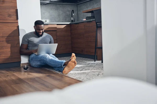 Konzentrierter dunkelhäutiger Mann blickt auf Bildschirm seines Laptops — Stockfoto