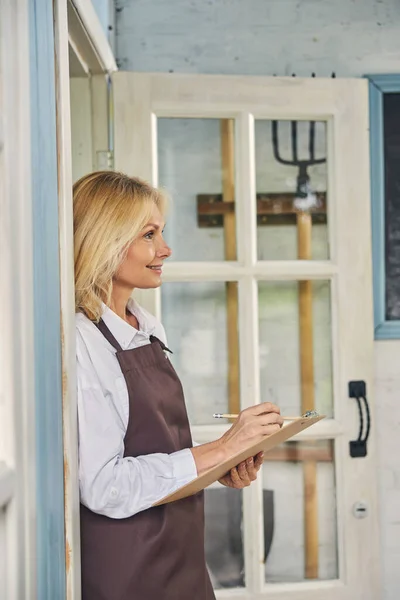 Усміхнена жінка-працівник стоїть у дверному отворі — стокове фото