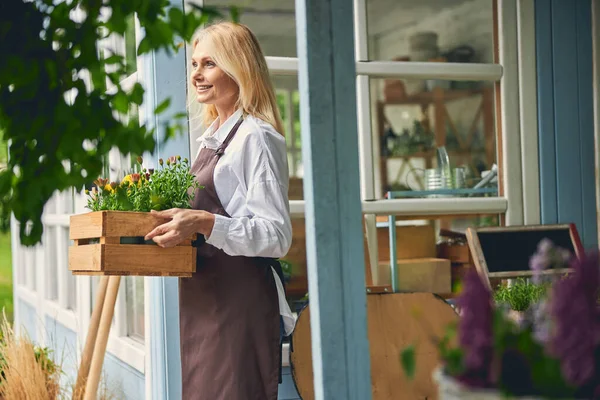 Kvinna med ringblommor och gasanier stående utanför — Stockfoto