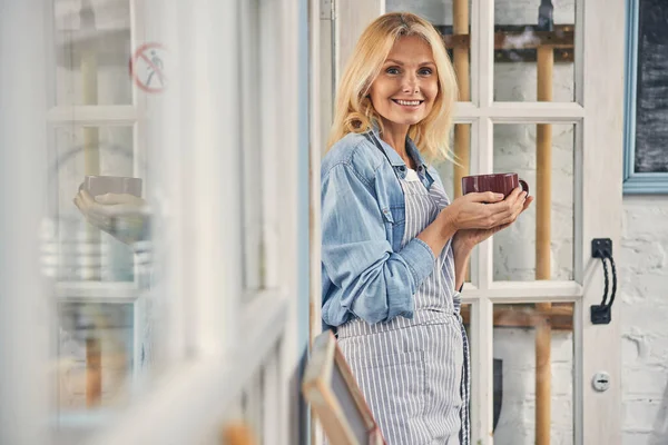 Lykkelig dame med en kopp kaffe som står utendørs – stockfoto