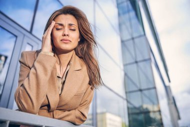 Paltolu güzel iş kadını dışarıda baş ağrısı çekiyor.