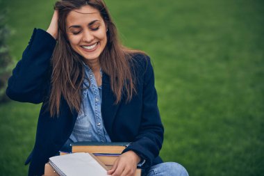 Çekici esmer bayan dışarıda kitaplarla kalıyor.