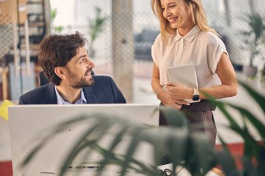 Neşeli genç adam iş yerinde bayan meslektaşıyla sohbet ediyor.