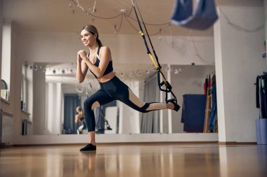 Genç bayan spor salonunda hareketsiz duruyor.