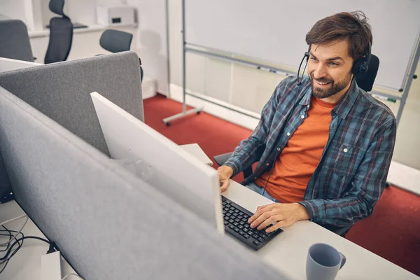 Knappe jongeman met behulp van computer in kantoor — Stockfoto