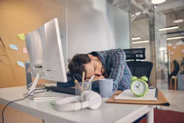 Wyczerpany, przepracowany młodzieniec drzemie w biurze — Zdjęcie stockowe