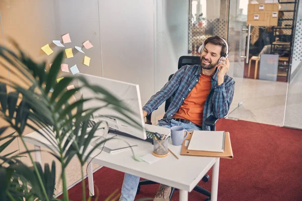 Fröhlicher junger Mann nutzt Computer bei der Arbeit — Stockfoto