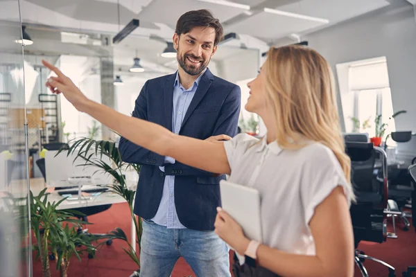 Joven alegre hombre y mujer discutiendo proyecto en el trabajo —  Fotos de Stock