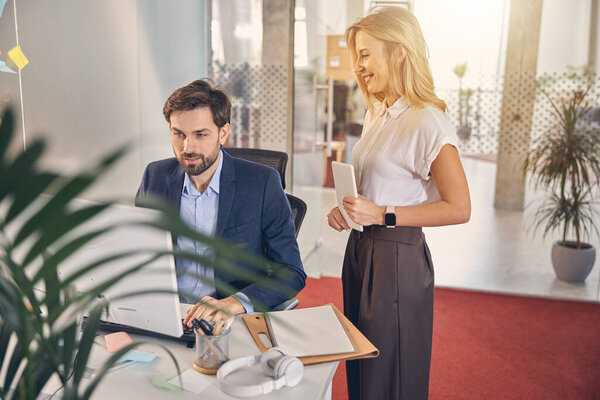 Handsome young man and charming woman working in office