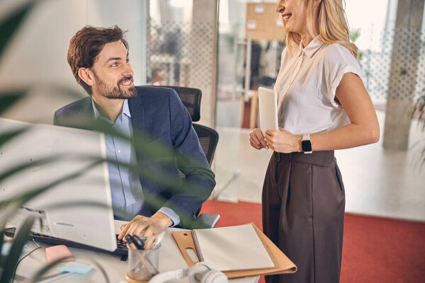 Cheerful businessman talking with female colleague at work