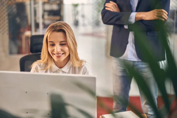 Fröhliche junge Frau nutzt Computer im modernen Büro — Stockfoto