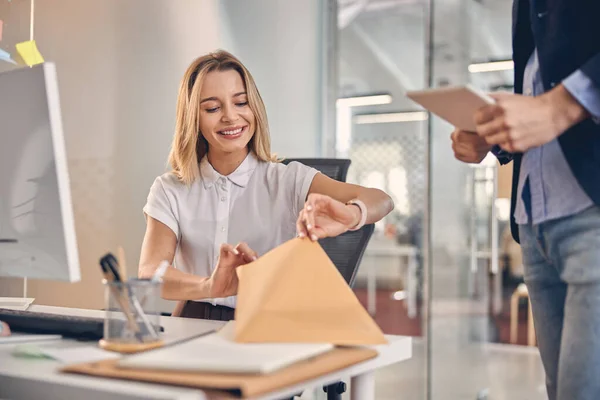 Vrolijke jonge vrouw die documenten op het werk controleert — Stockfoto