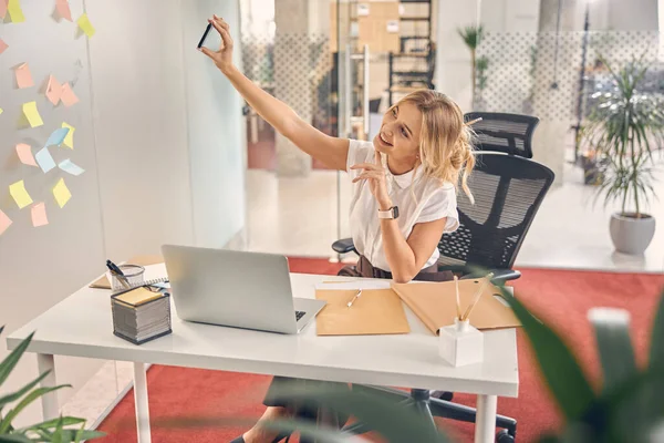 Sonriente joven mujer haciendo selfie en el trabajo —  Fotos de Stock