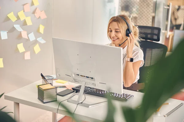 Vacker ung kvinna i headset arbetar på kontoret — Stockfoto