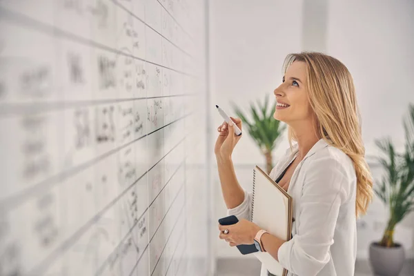 Glada ung kvinna studerar task board i ämbetet — Stockfoto