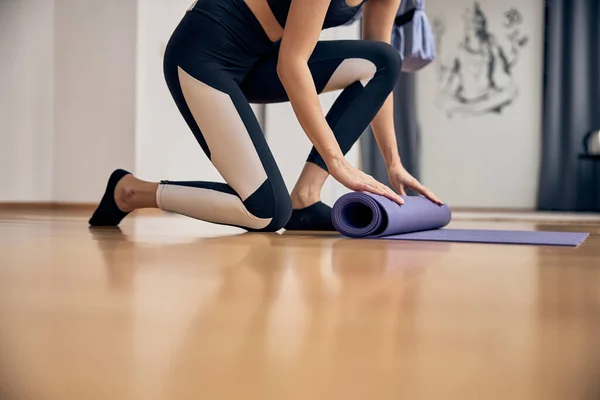 Mulher magra rolando tapete de ioga após sessão — Fotografia de Stock