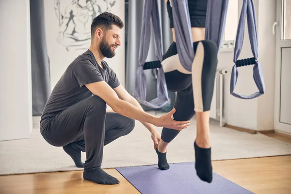 Male assisting female while doing exercise in studio — Stock Photo, Image