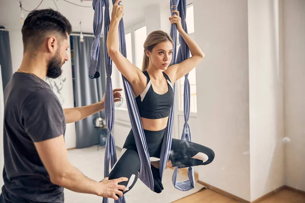 Lady praktiserar anti-gravitationyoga assisterad av sin instruktör — Stockfoto