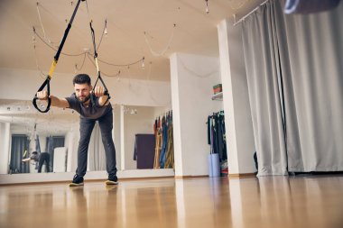 Erkek sporcu geniş duruşlu bir kalça menteşesi sergiliyor.