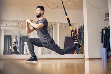 Rüya gibi genç bir atlet TRX hamlesi yapıyor.