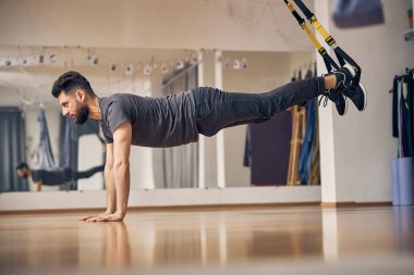 Odaklanmış erkek sporcu kalas egzersizi yapıyor.