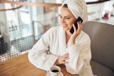 Akıllı telefondan konuşan bornozlu bir kadın.