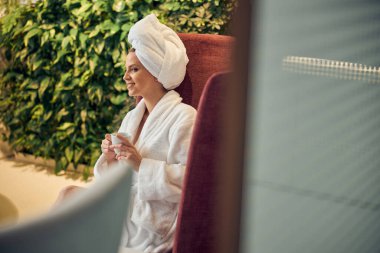 Ellerinde fincanı olan mutlu bir bayan gözlerini dikip bakıyor.