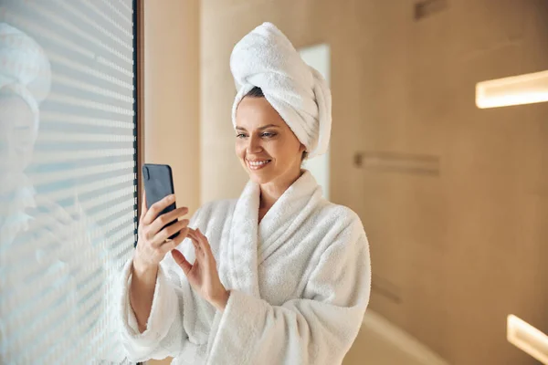 En glad kvinna i badrock använder sin pryl. — Stockfoto