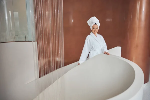 Mulher alegre em um roupão de banho olhando em frente — Fotografia de Stock
