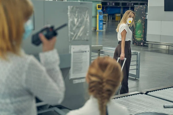 Attentive blonde woman looking at airport workers