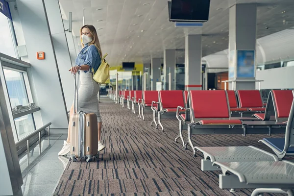 Uppmärksam ung kvinna som står nära fönstret — Stockfoto