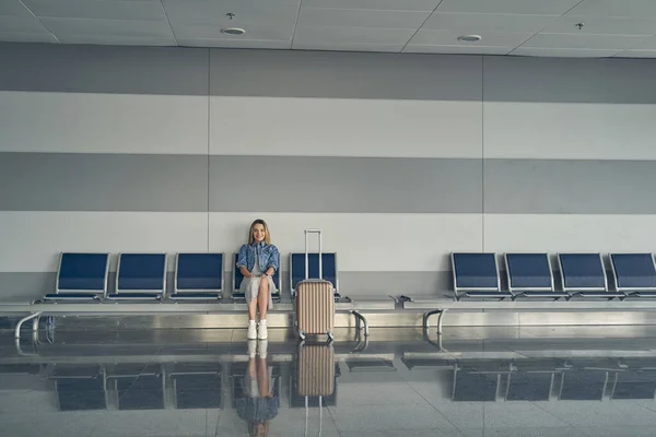 Joyful female person sitting in departure lounge — Stock Photo, Image