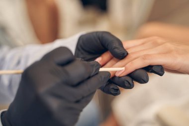 Kuaför uzmanının eldivenli elleri manikür yapıyor.