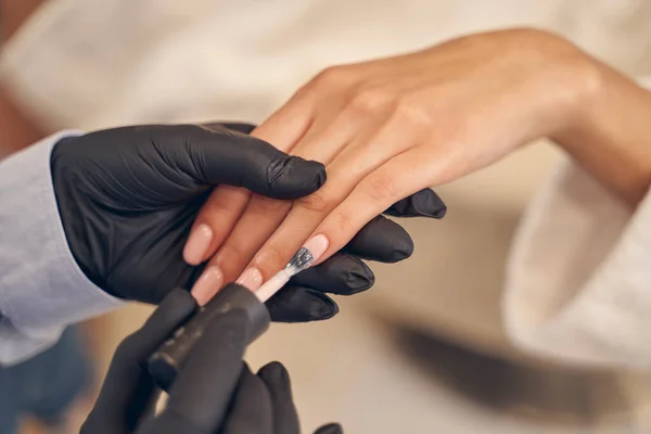 Mujer joven durante el tratamiento de manicura en salón de belleza —  Fotos de Stock