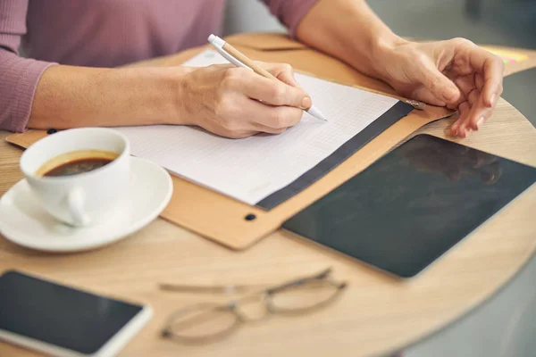 Upptagen kvinna gör anteckningar under arbetet — Stockfoto