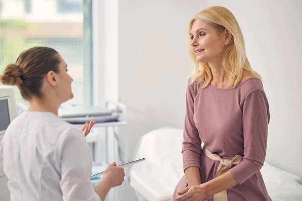 Aufmerksame blonde Frau hört ihrem Arzt zu — Stockfoto