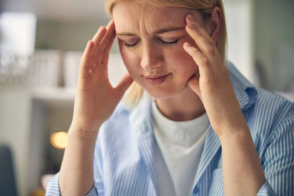 Överarbetad blond kvinna känner smärta i huvudet — Stockfoto